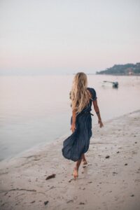 photo of woman walking on seashore