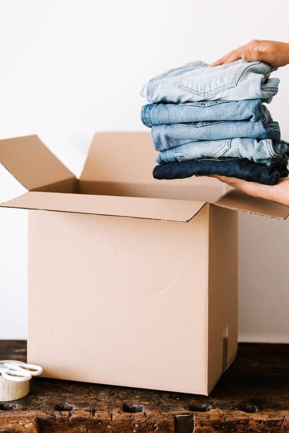 crop person packing jeans into carton container