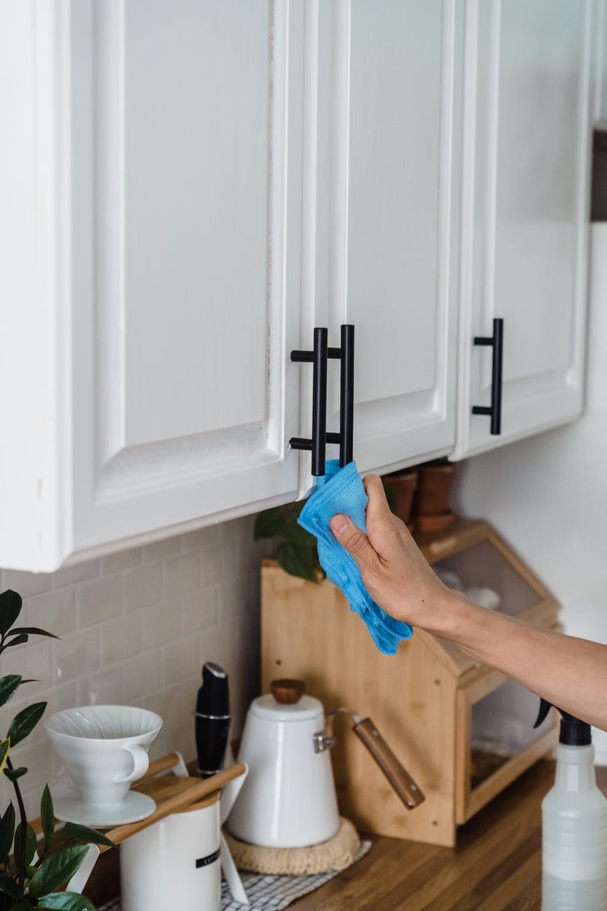 a person wiping the handles of a kitchen cabinet