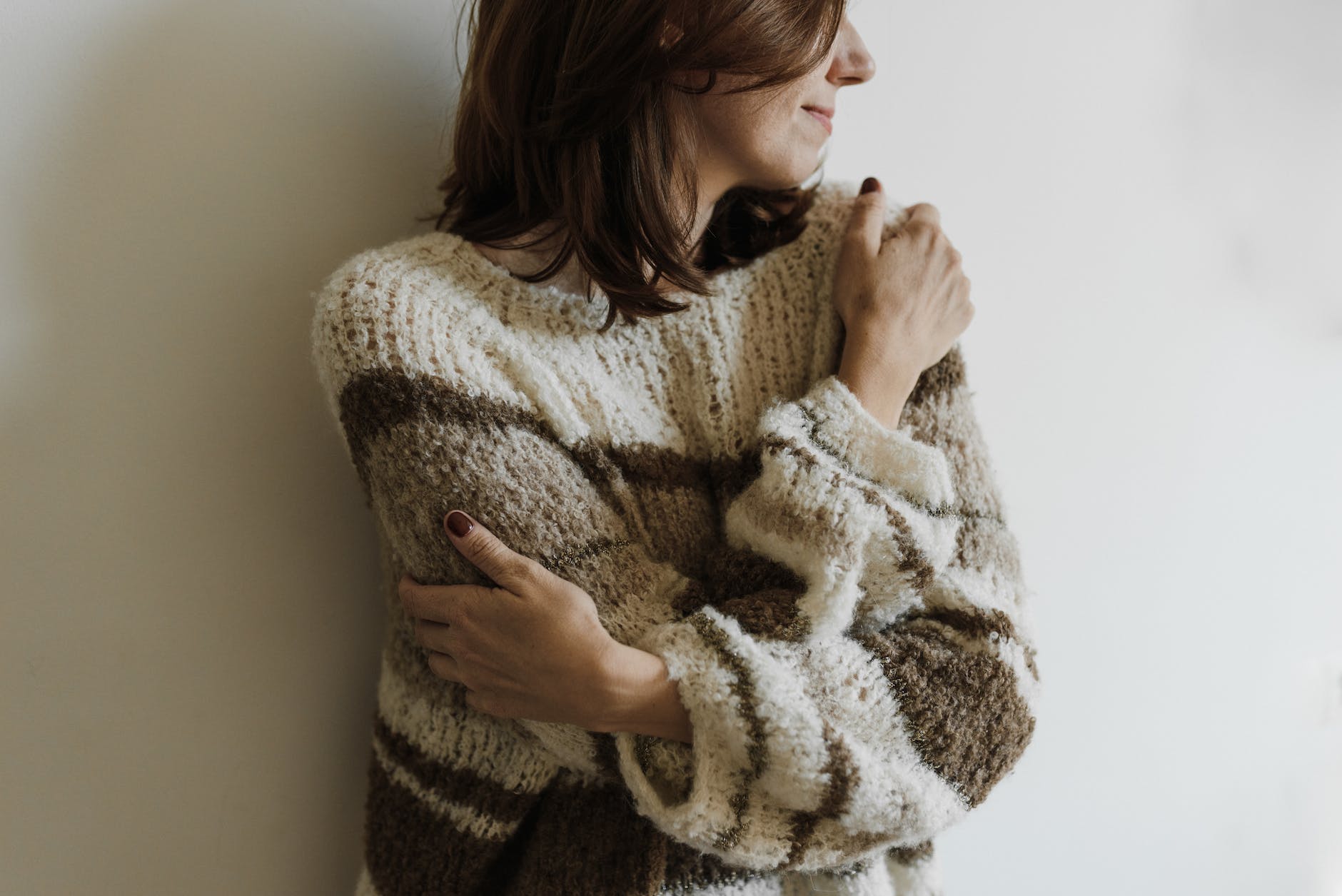 a woman in knit sweater hugging self