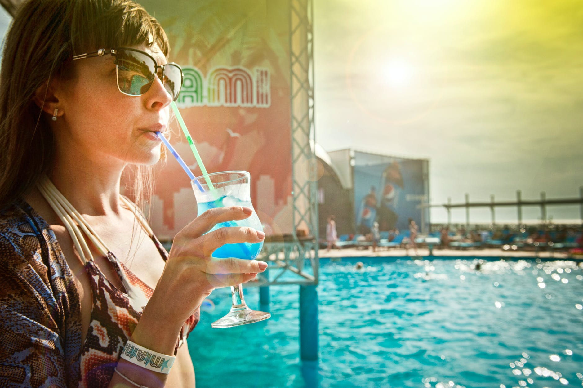 woman zipping blue drinks beside in ground pool